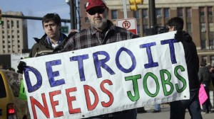Chrysler Transport worker Theisen carries a "Detroit Needs Jobs" sign as he joins a demonstration demanding jobs in Detroit